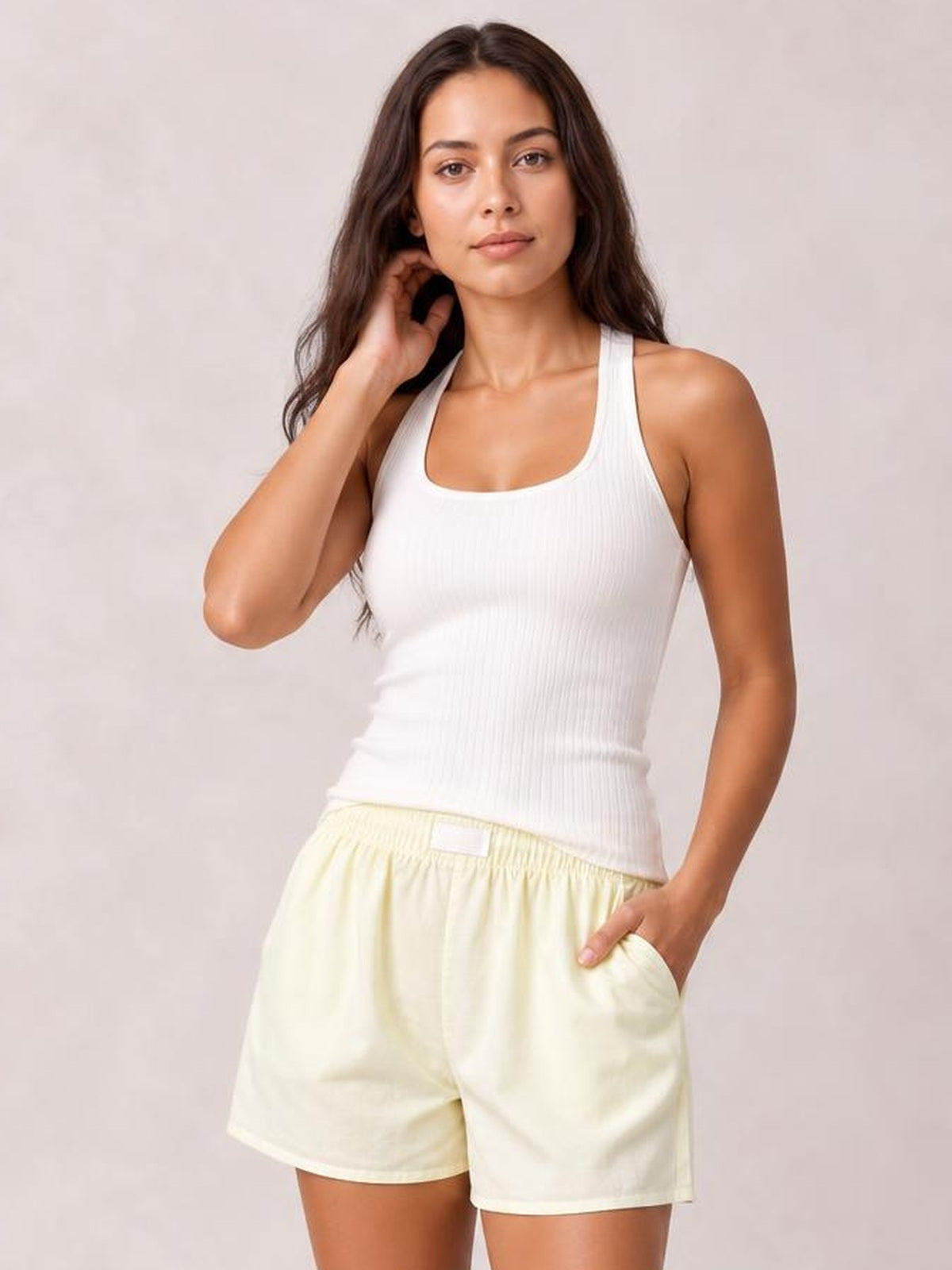 Model wearing pale yellow elastic waist shorts with a relaxed straight-leg silhouette, side pockets, and a casual above-knee length.