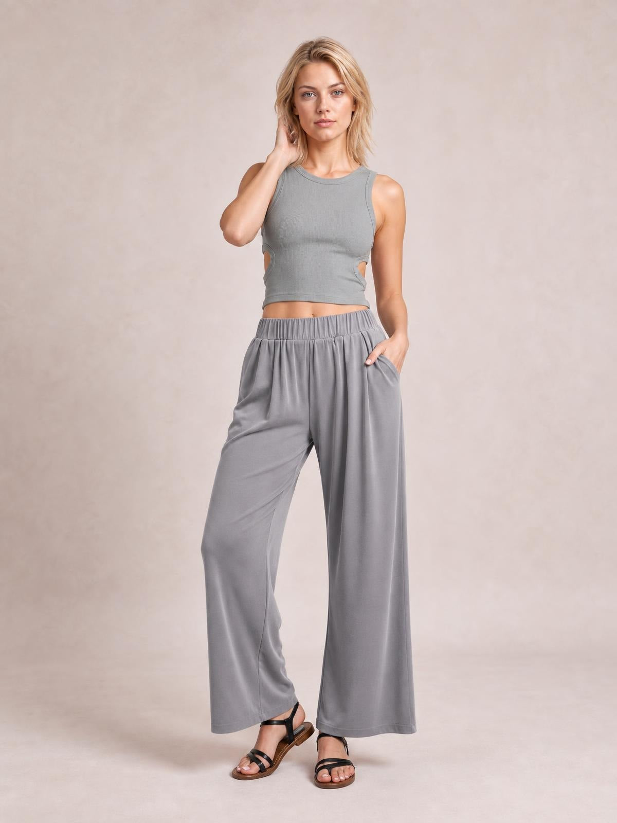 Model poses in gray elastic-waist wide-leg pants with flowing full-length legs and side pockets, one hand tucked into a pocket.