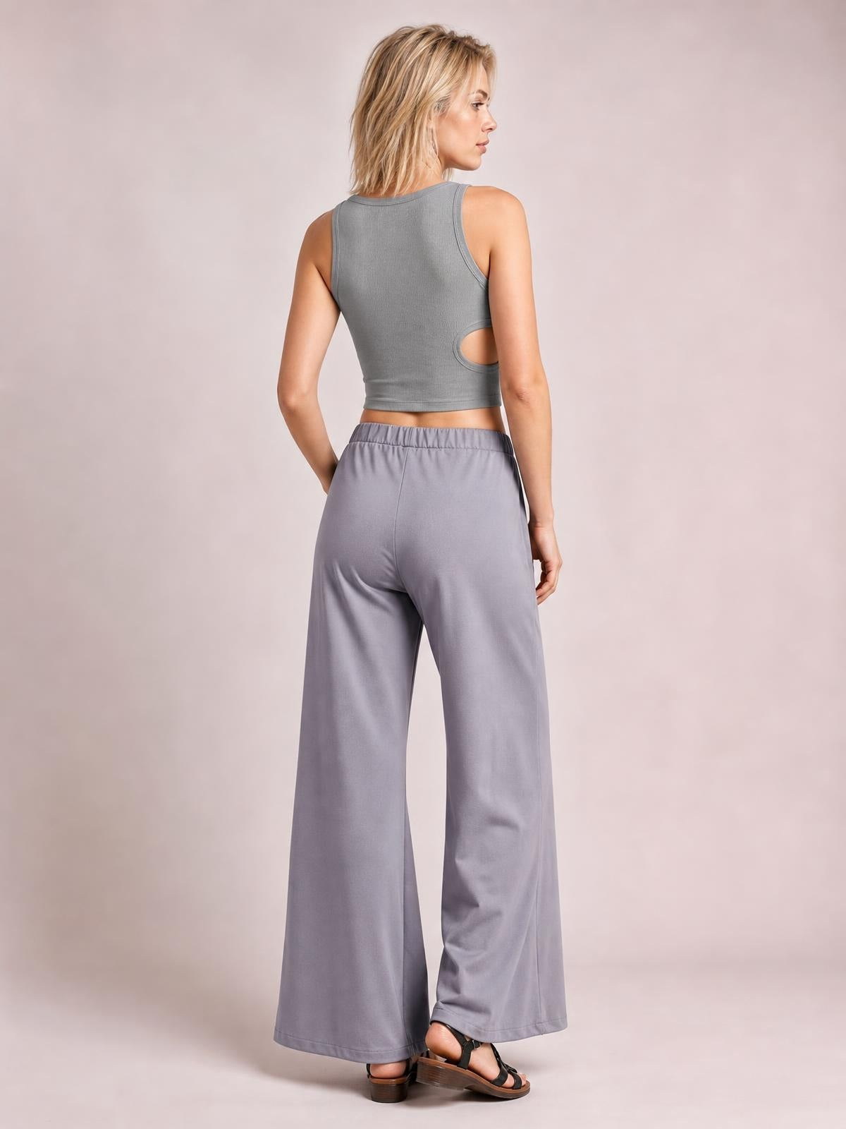 Model poses turned away in gray elastic waist wide leg pants with a relaxed silhouette, full-length hems, and side pockets.