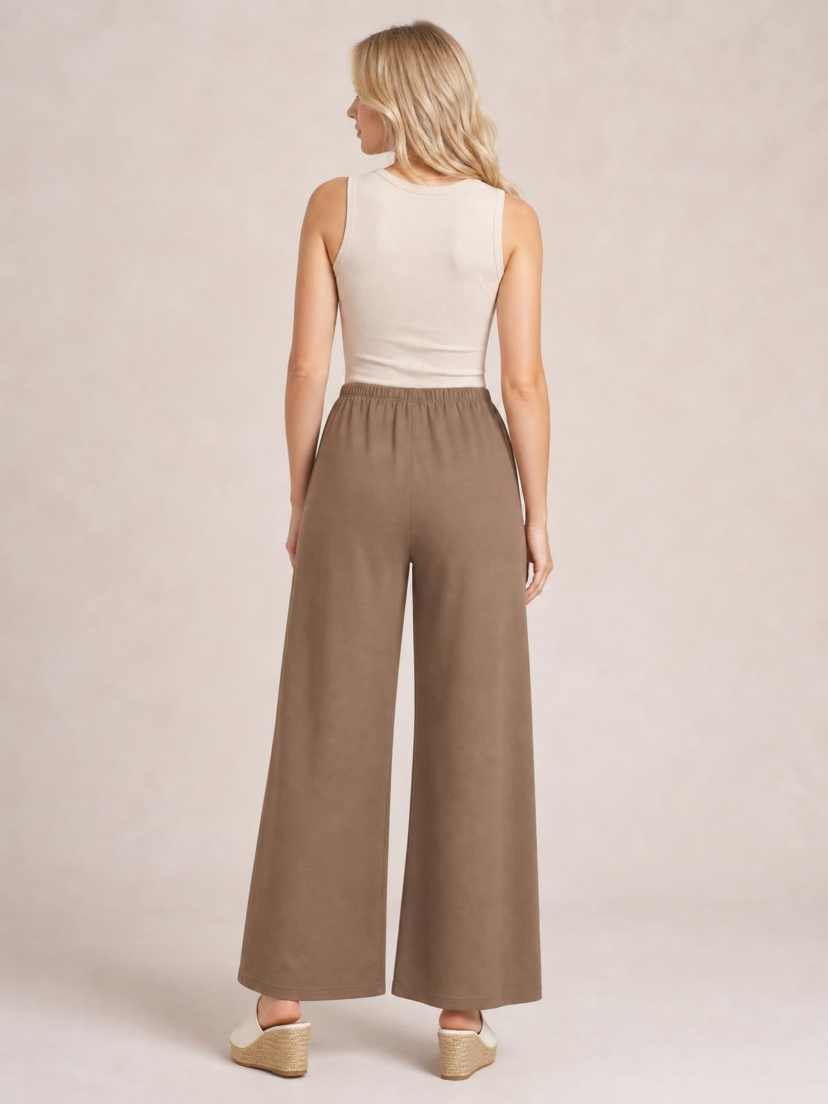 Model shown from the back wearing taupe elastic waist wide leg pants with a relaxed full-length silhouette and visible side pockets.