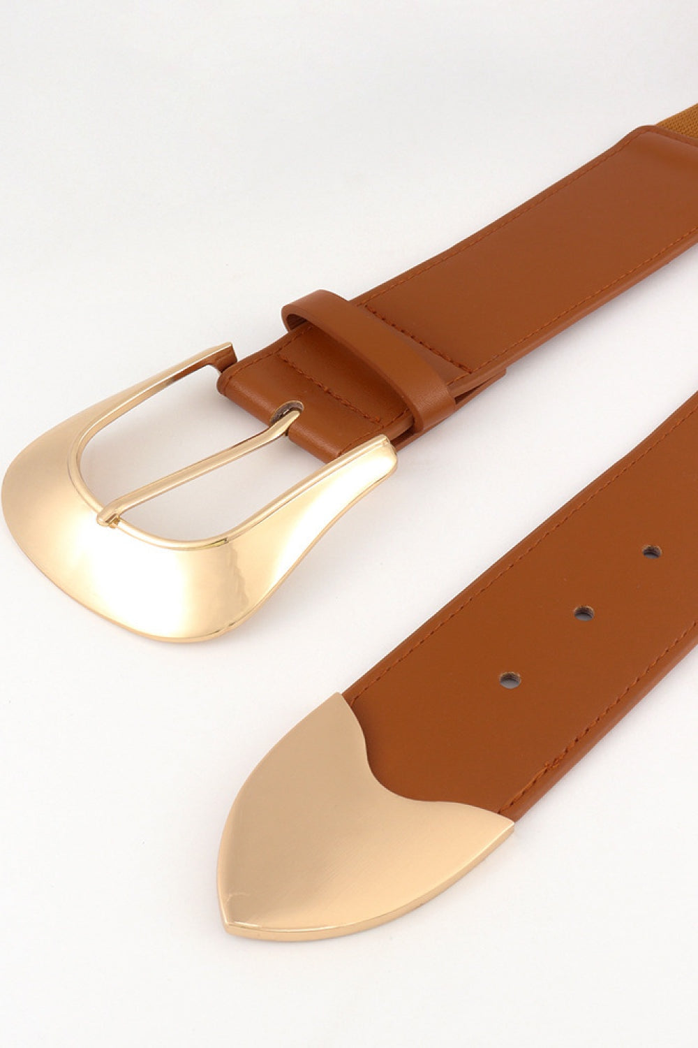 Close-up of a wide brown PU belt with an elastic strap, polished gold-tone buckle, stitched edges, perforated fastening holes, and a rounded metal end detail.