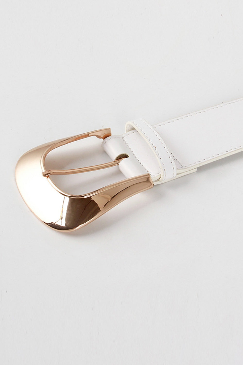 Close-up of a white wide PU belt with a polished rose-gold zinc alloy buckle, stitched edges, coordinating belt loop, and rounded end detail.