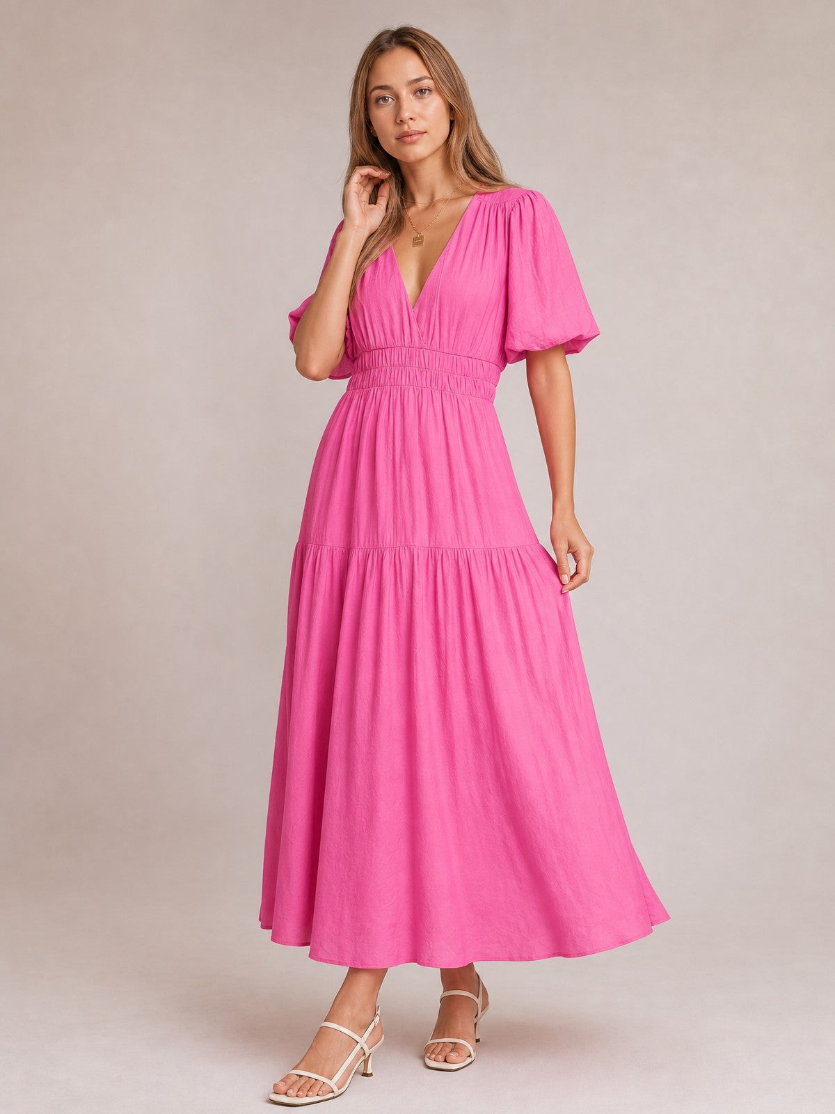 Model poses in a bright pink puff sleeve V-neck midi dress with a smocked waist, tiered flowing skirt, and feminine A-line silhouette.