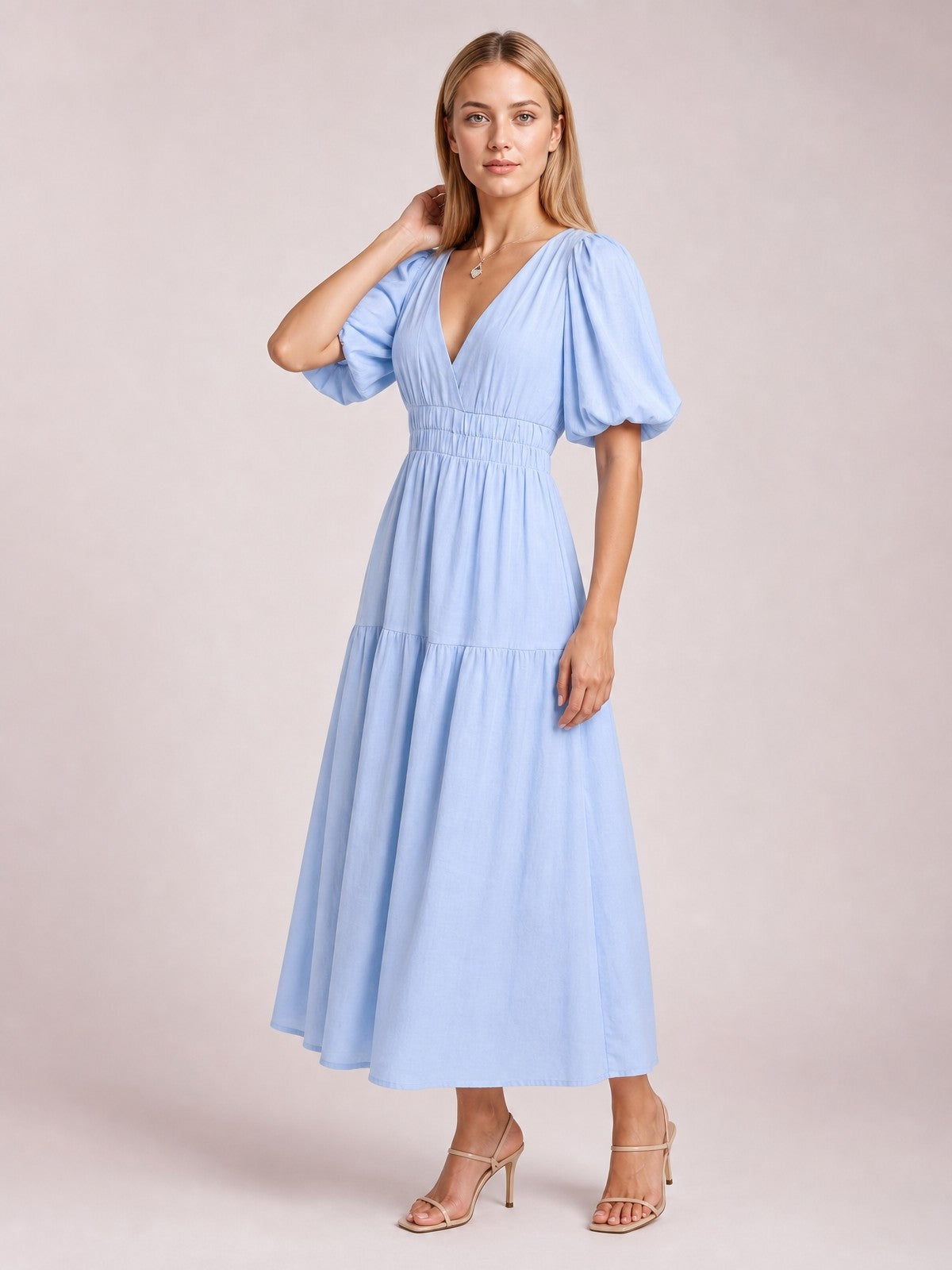 Model poses in a light blue puff sleeve V-neck midi dress with a smocked waist, tiered flowing skirt, and feminine A-line silhouette.