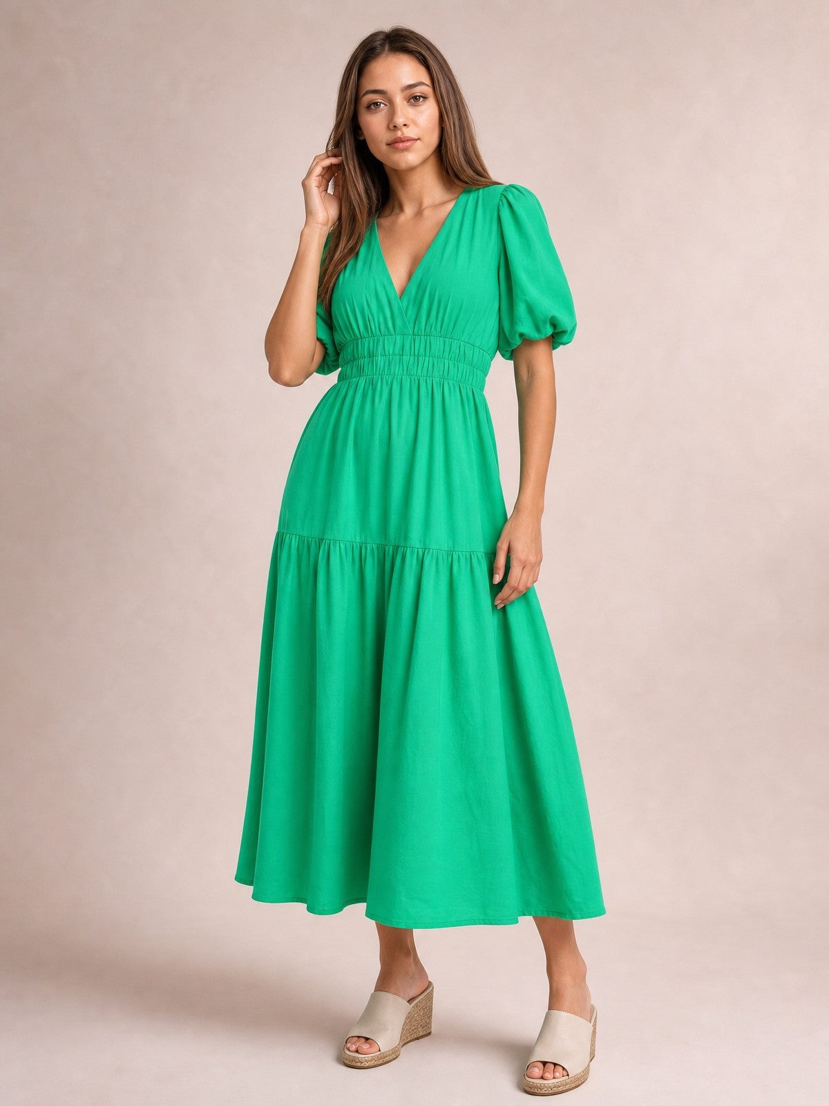 Model poses in a vibrant green puff sleeve V-neck midi dress with a smocked waist and flowing tiered skirt, paired with wedge sandals.