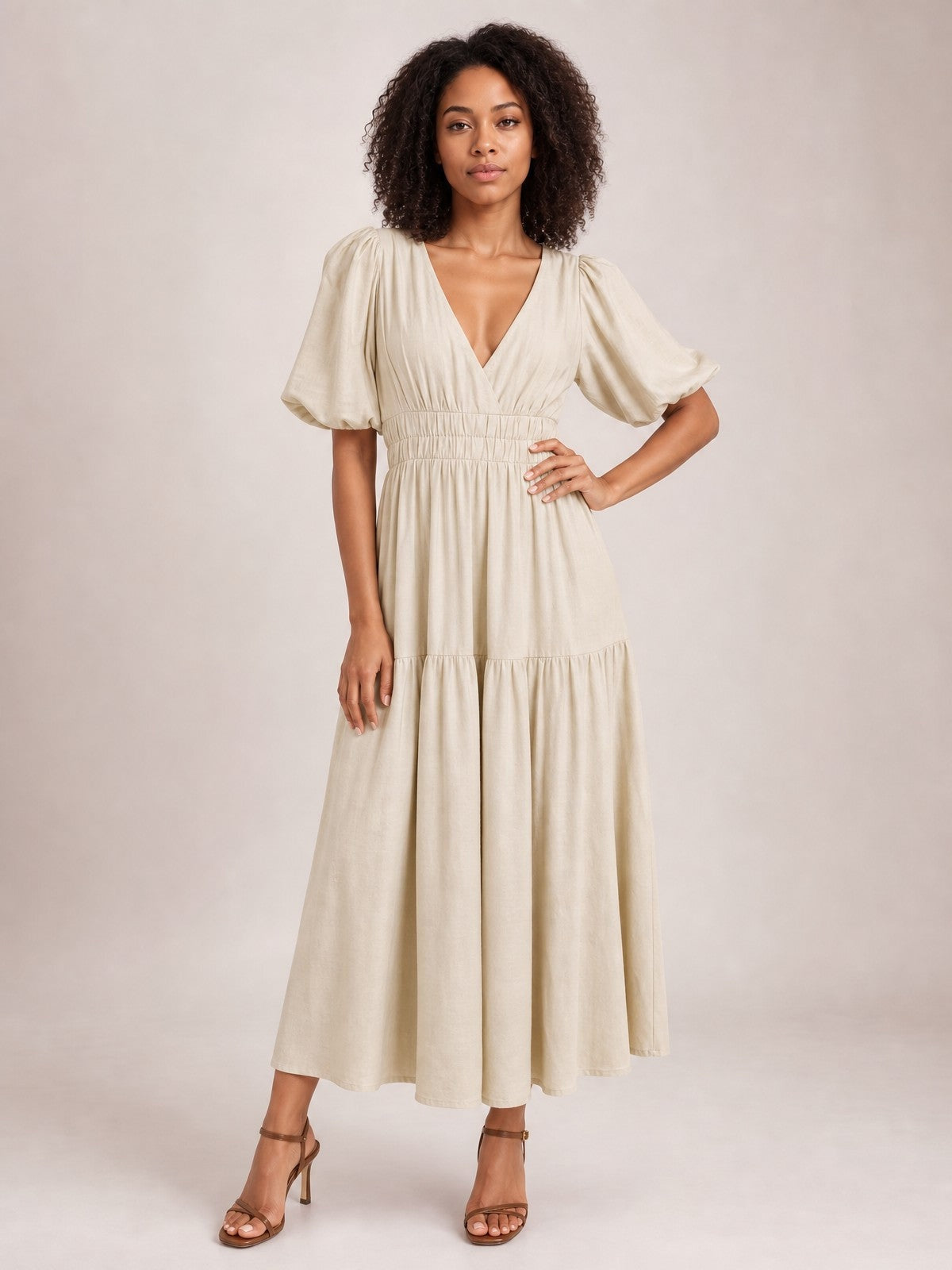 A model poses in an elegant cream puff sleeve V-neck midi dress with a smocked waist, tiered flowing skirt, and relaxed feminine silhouette.