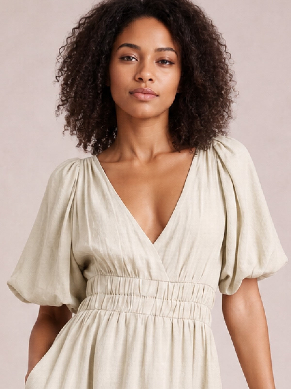 Model wears an elegant ivory V-neck midi dress with gathered puff sleeves, a smocked waist, and a flowing tiered skirt in a feminine silhouette.