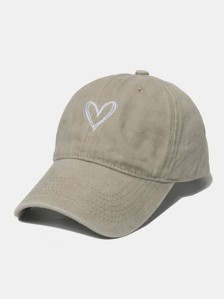 Taupe washed cotton baseball cap with a six-panel silhouette, curved brim, tonal stitching, and a contrasting embroidered heart on the front.