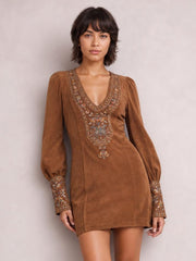 A model stands in a brown embroidered mini dress with a V-neckline, lantern sleeves, gathered cuffs, and a straight, fitted silhouette.