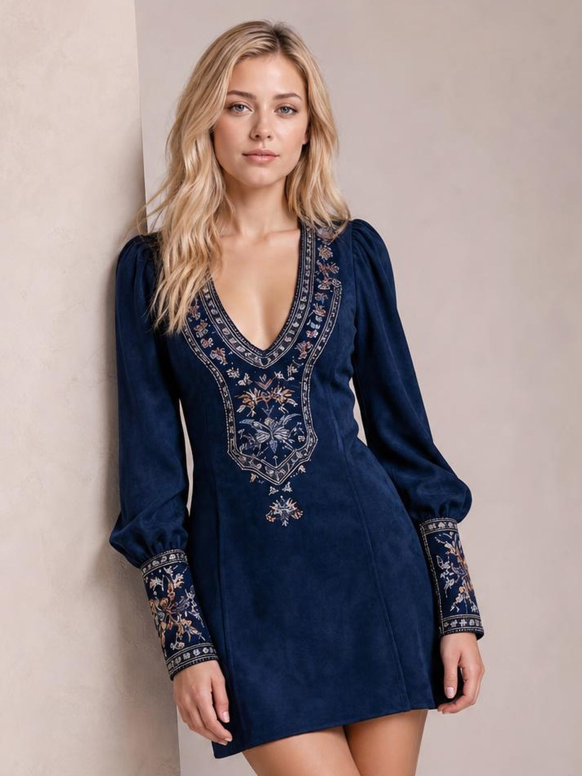 A model stands facing the camera in a navy embroidered mini dress with a deep V-neck, lantern sleeves, patterned cuffs, and a straight silhouette.