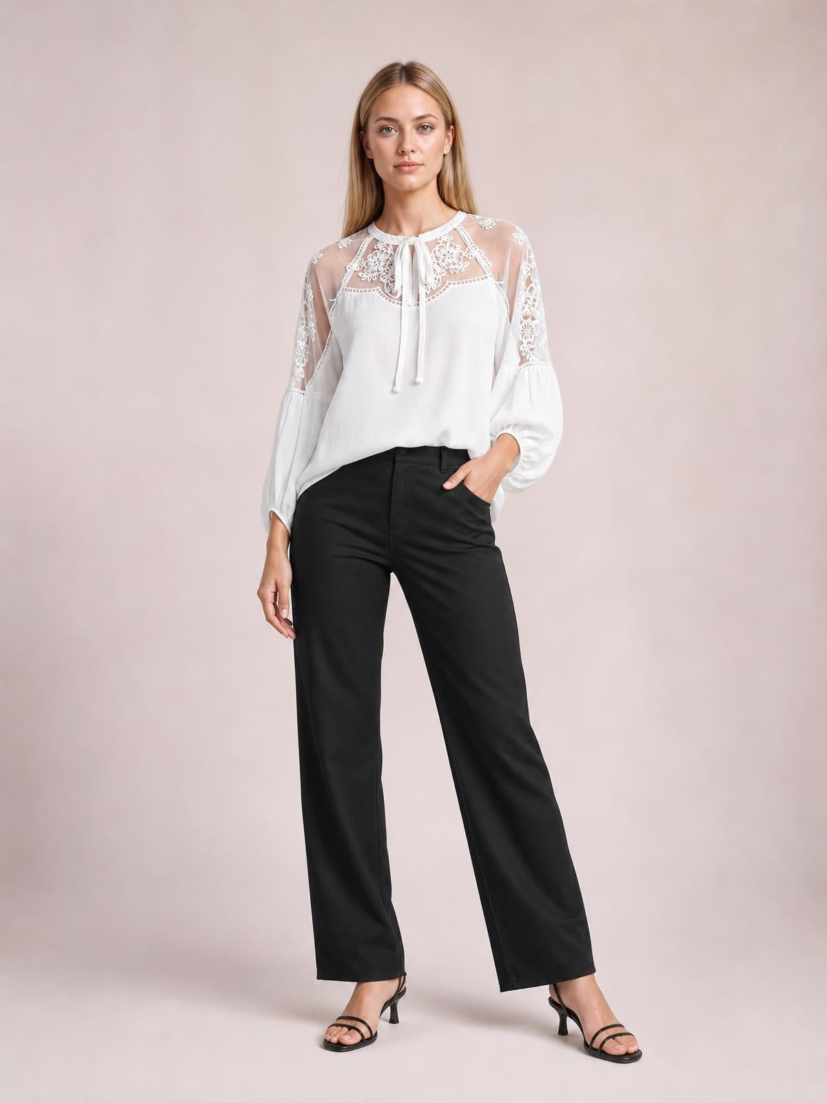 Model wears a white embroidered tie-neck blouse with floral mesh yoke, raglan puff sleeves, and a relaxed regular-length silhouette, posing with one hand in her pocket.