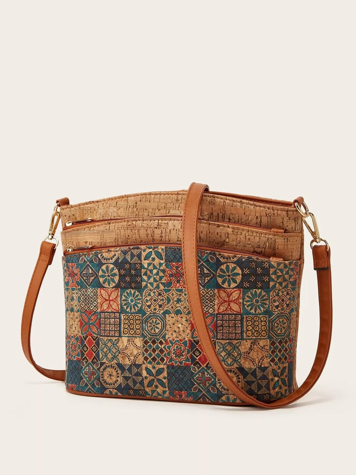 A medium PU leather crossbody bag features a multicolor ethnic patchwork and tree bark pattern, multiple zip pockets, and tan adjustable straps.