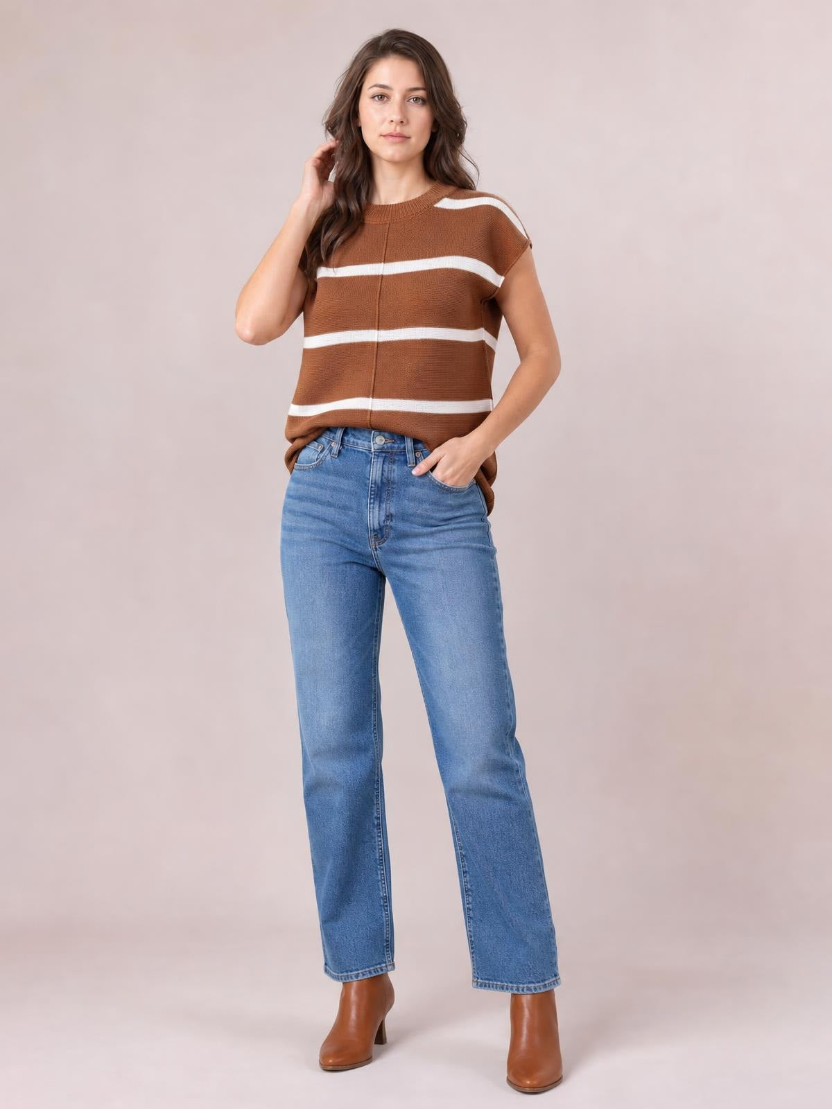 Model poses in a brown knit top with white contrast stripes, round neck, short sleeves, exposed center seam, and a relaxed silhouette.