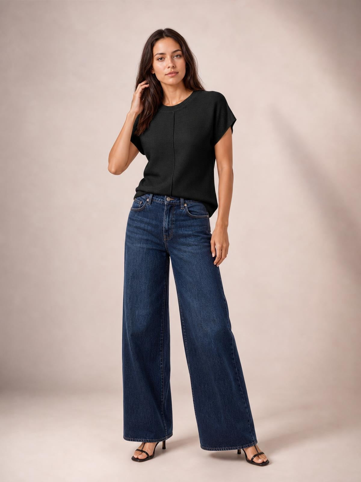 Model wearing a black exposed-seam round-neck short-sleeve sweater with a relaxed silhouette, paired with wide-leg jeans and sandals.