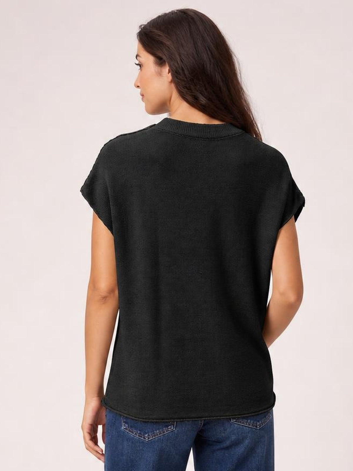 Model shown from the back in a black short-sleeve sweater with a round ribbed neck, rolled cuffs, exposed seams, and a relaxed silhouette.