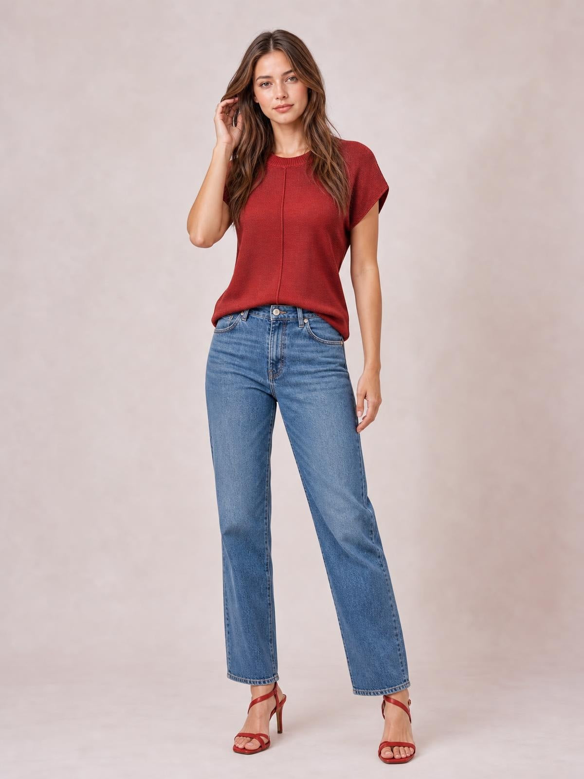 Model poses in a red exposed seam round neck short sleeve sweater with a relaxed straight silhouette and ribbed neckline.