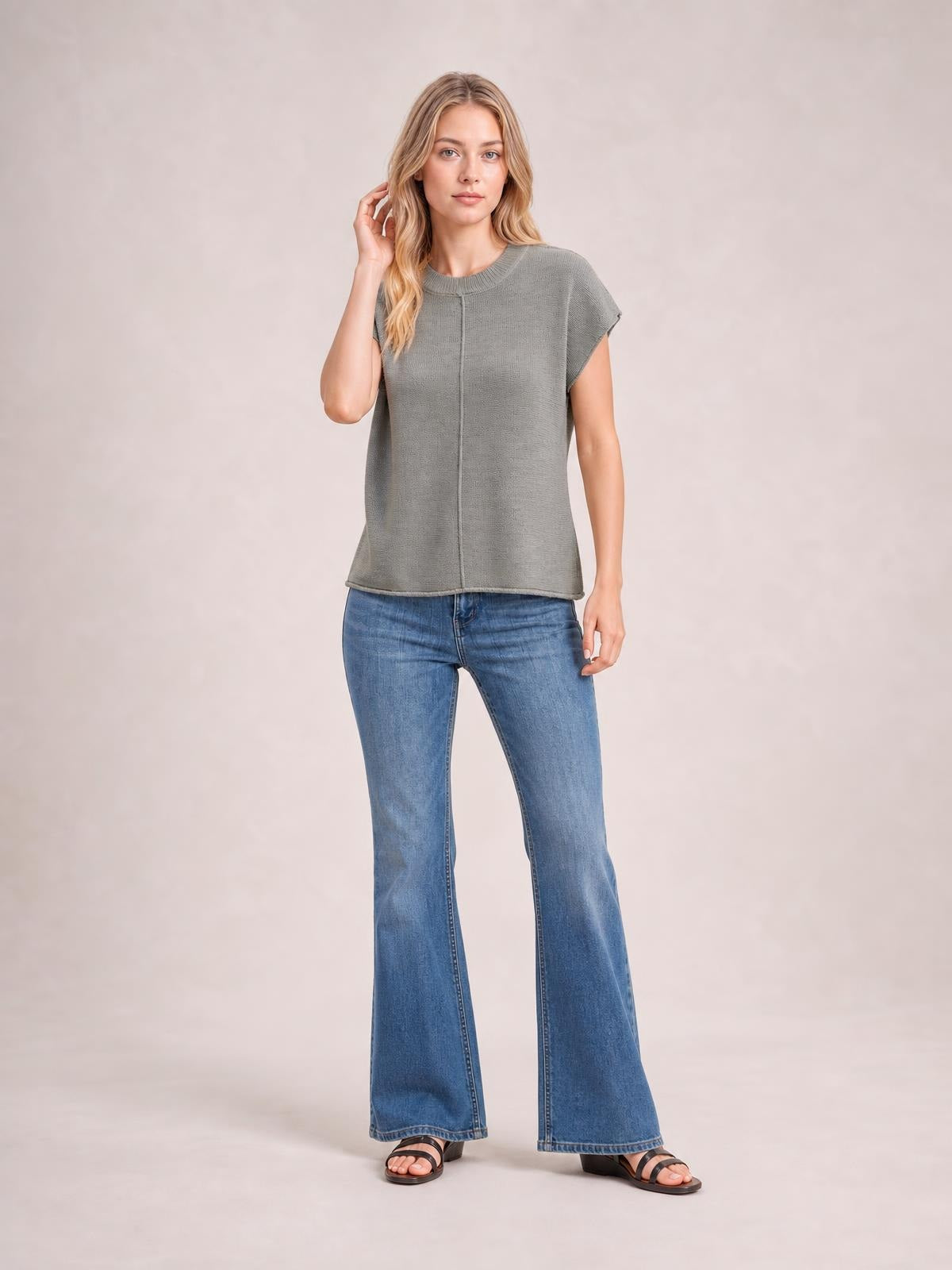 A model poses in a gray short-sleeve sweater with a round neck, exposed center seam, relaxed straight silhouette, and subtly finished edges.