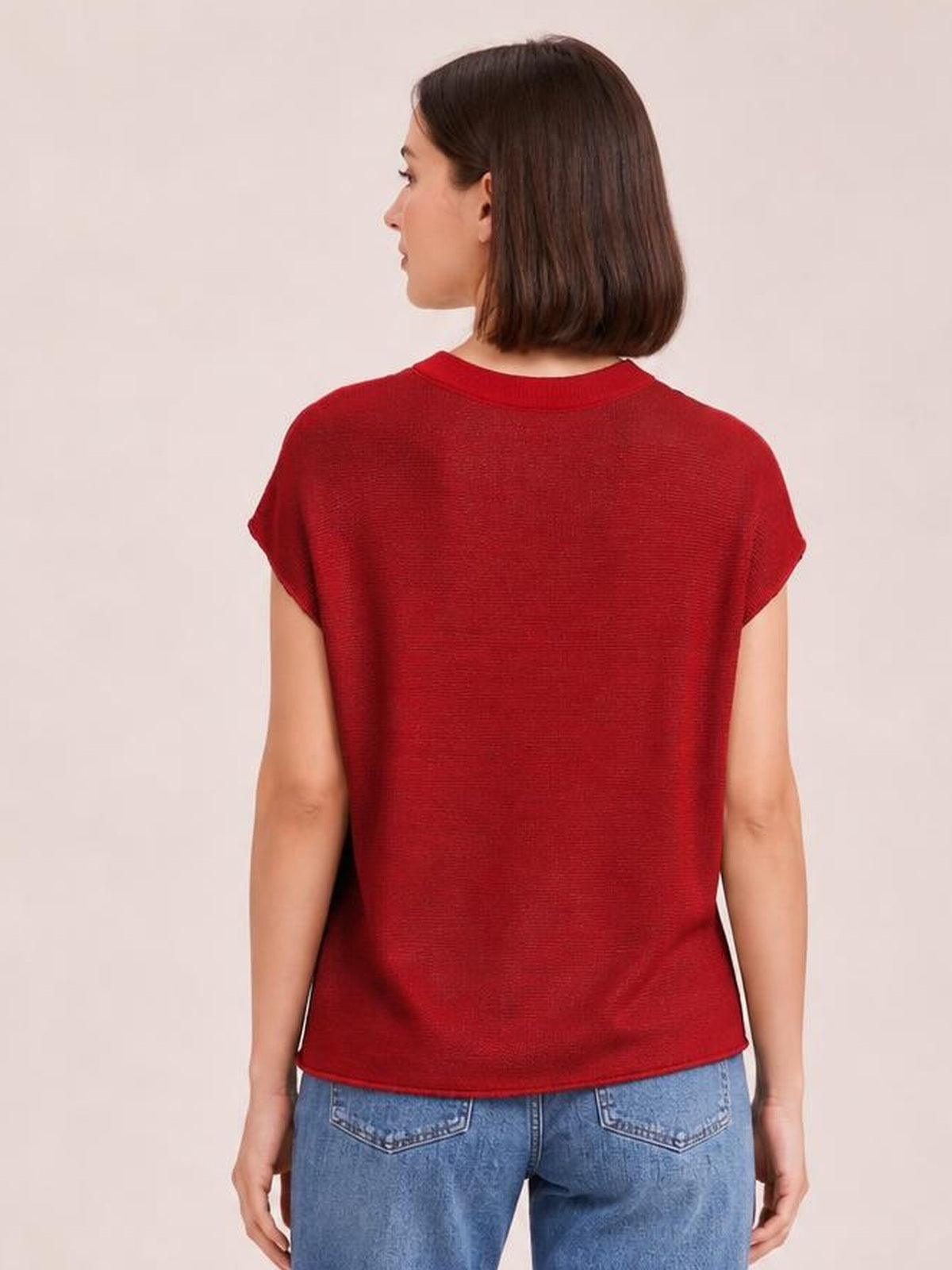 Model shown from the back in a red exposed-seam round-neck sweater with short sleeves and a relaxed straight silhouette.