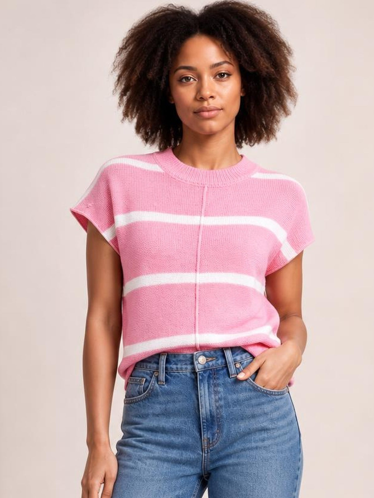 Model wearing a pink striped round neck knit top with an exposed center seam, short sleeves, and a relaxed straight silhouette styled with jeans.