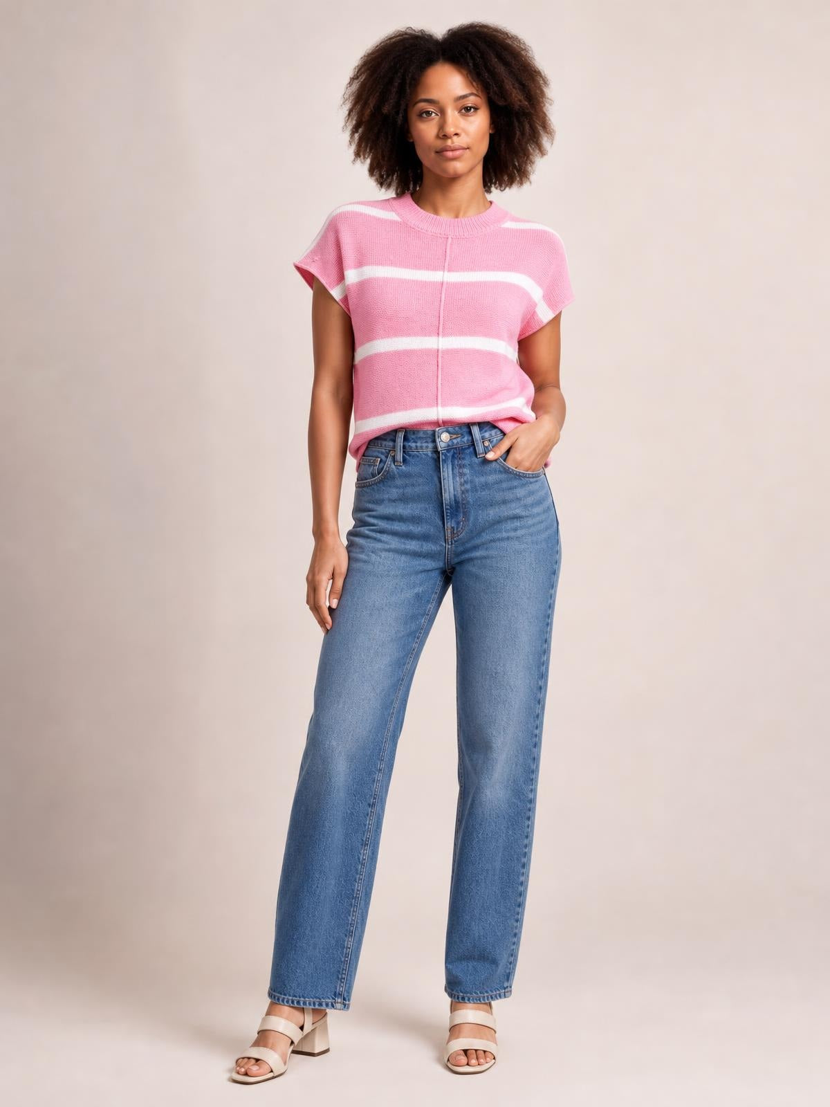 Model wearing a pink striped round neck knit top with exposed center seam, short sleeves, and a relaxed silhouette, paired with jeans.