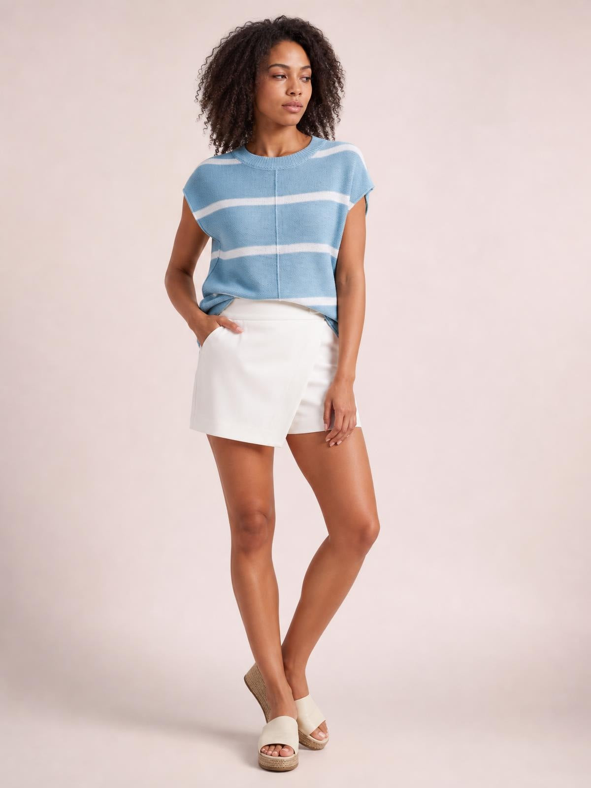 Model wears a light blue and white striped knit top with a round neck, exposed center seam, short sleeves, and a relaxed boxy silhouette.