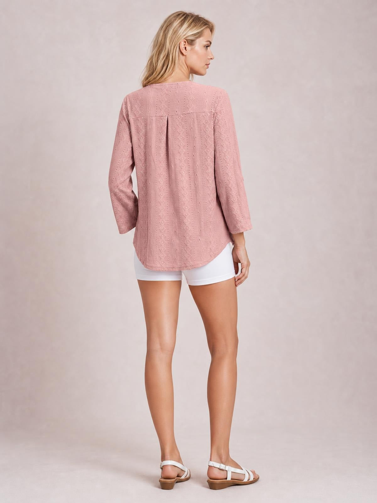 Model shown from the back wears a dusty pink eyelet top with a seamed yoke, relaxed silhouette, three-quarter sleeves, and a curved hem.