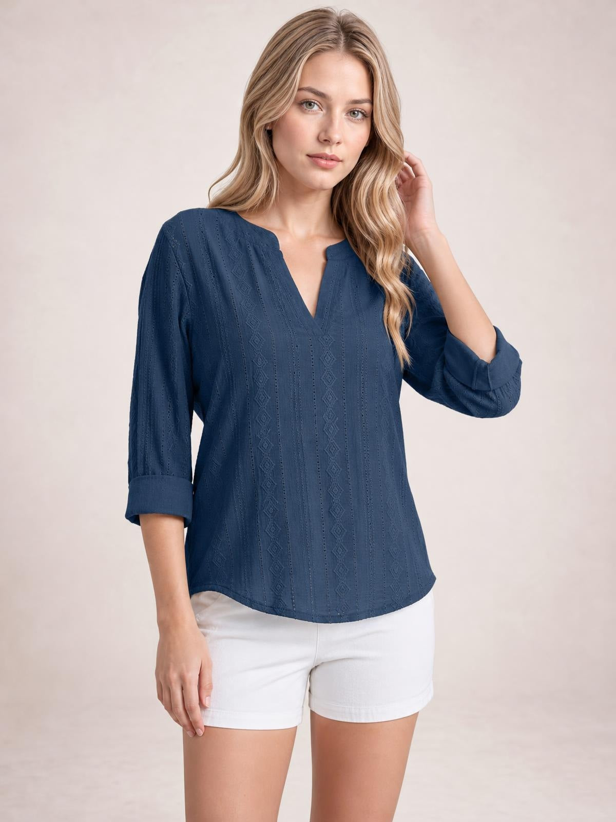 Model wearing a navy blue eyelet top with a notched neckline, vertical patterned texture, relaxed silhouette, and rolled tab sleeves.