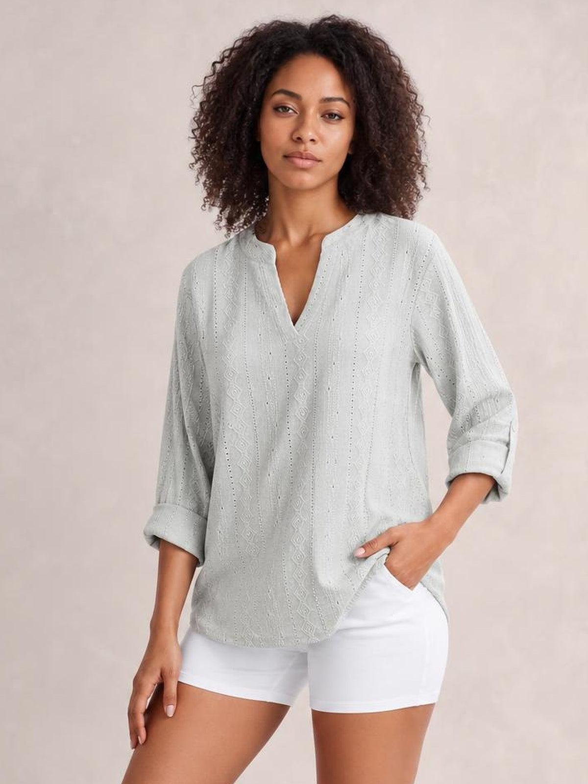 A model stands in a light gray eyelet top with a notched neckline, rolled-tab three-quarter sleeves, and a relaxed straight silhouette.