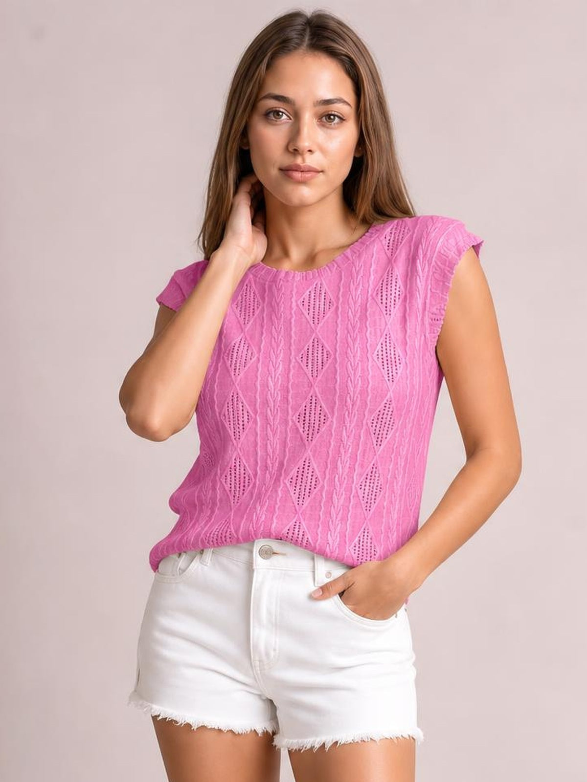 Model poses in a pink eyelet top with a round neck, textured diamond pattern, cap sleeves, and a relaxed straight silhouette.