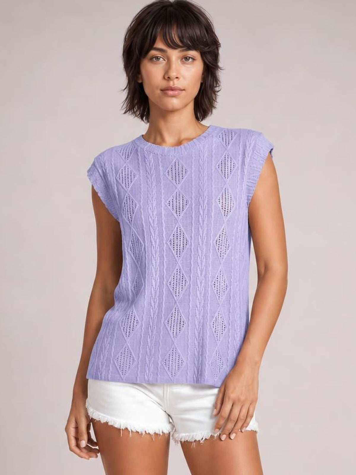 Model wearing a lavender eyelet top with a round neck, cap sleeves, diamond-patterned construction, and a relaxed straight silhouette, standing with arms at her sides.