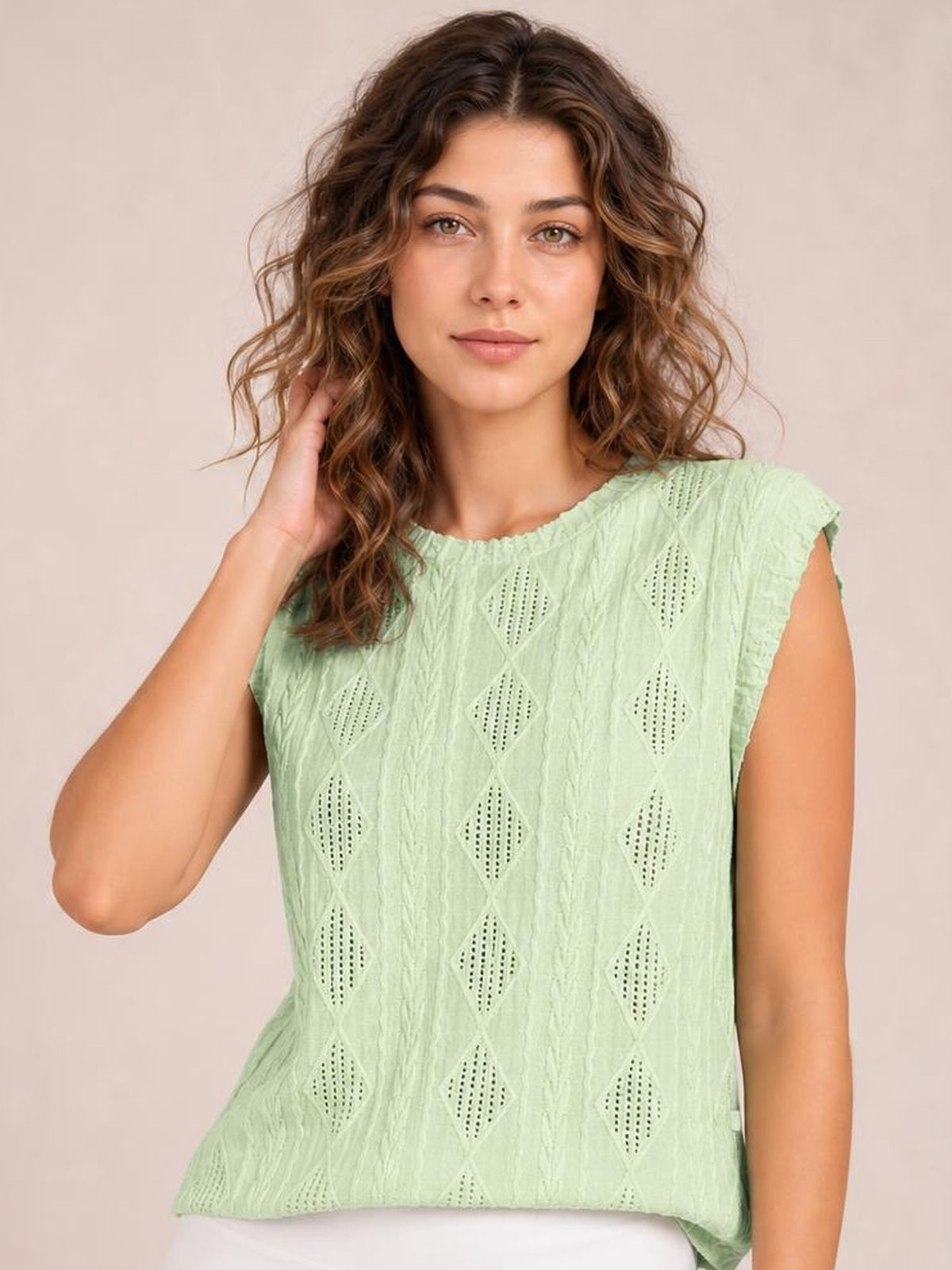 Model poses in a mint green eyelet top with a round neck, cap sleeves, relaxed straight silhouette, and diamond cutout pattern.