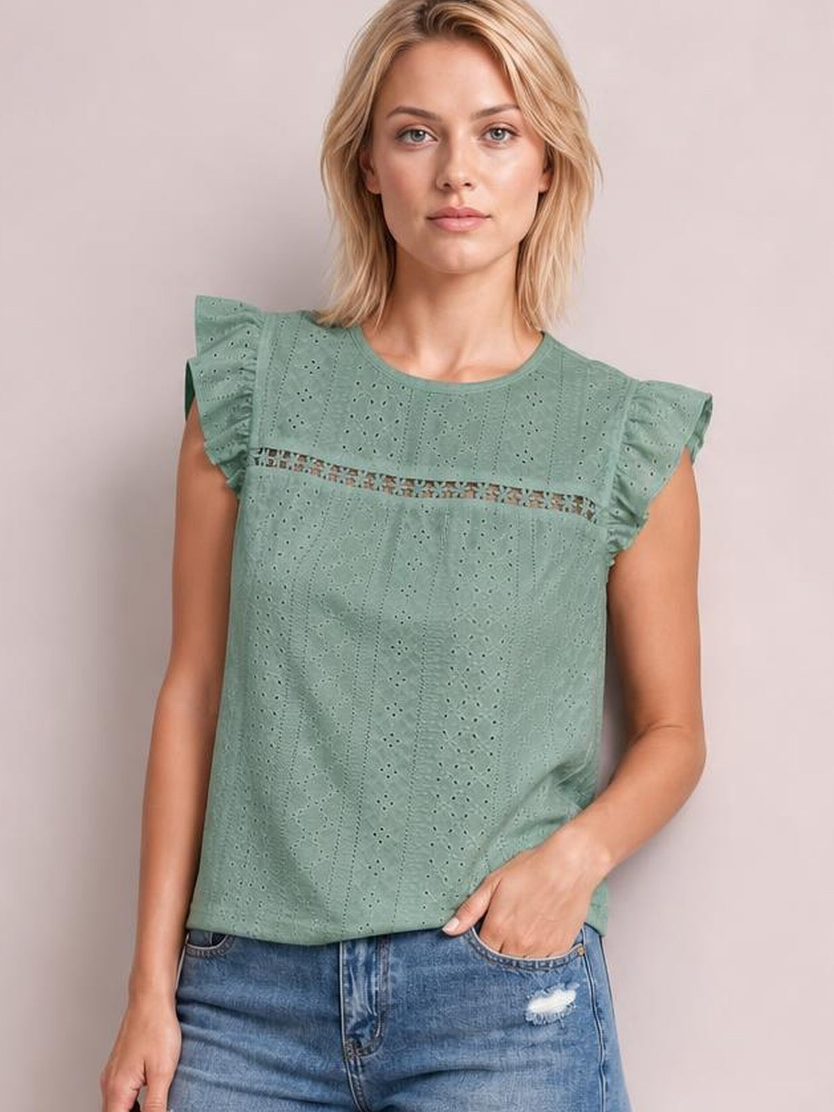 Model wears a sage green eyelet round neck top with ruffled cap sleeves, horizontal cutout trim, and a relaxed straight silhouette.