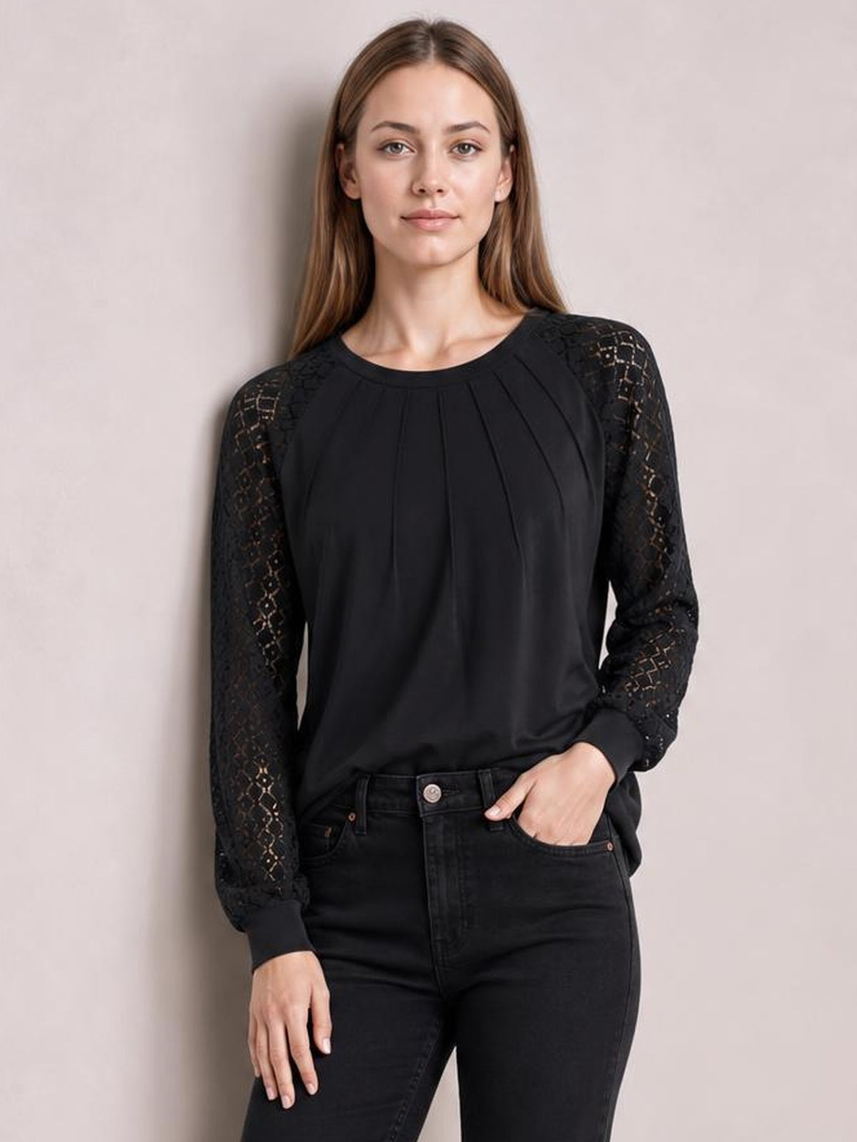 A model wears a black eyelet round neck long sleeve blouse with semi-sheer patterned sleeves, gathered front detail, and a relaxed silhouette.
