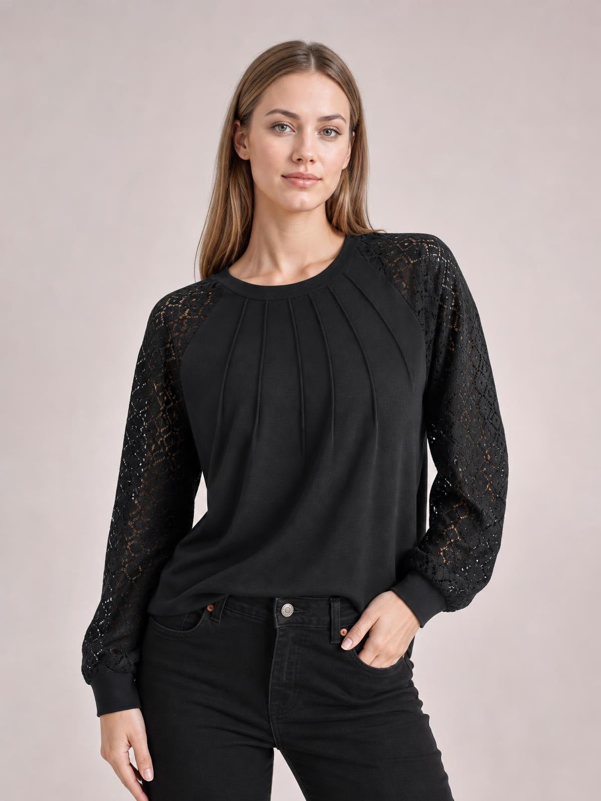 Model wearing a black eyelet round neck long sleeve blouse with semi-sheer lace sleeves, pleated front construction, and a relaxed silhouette.