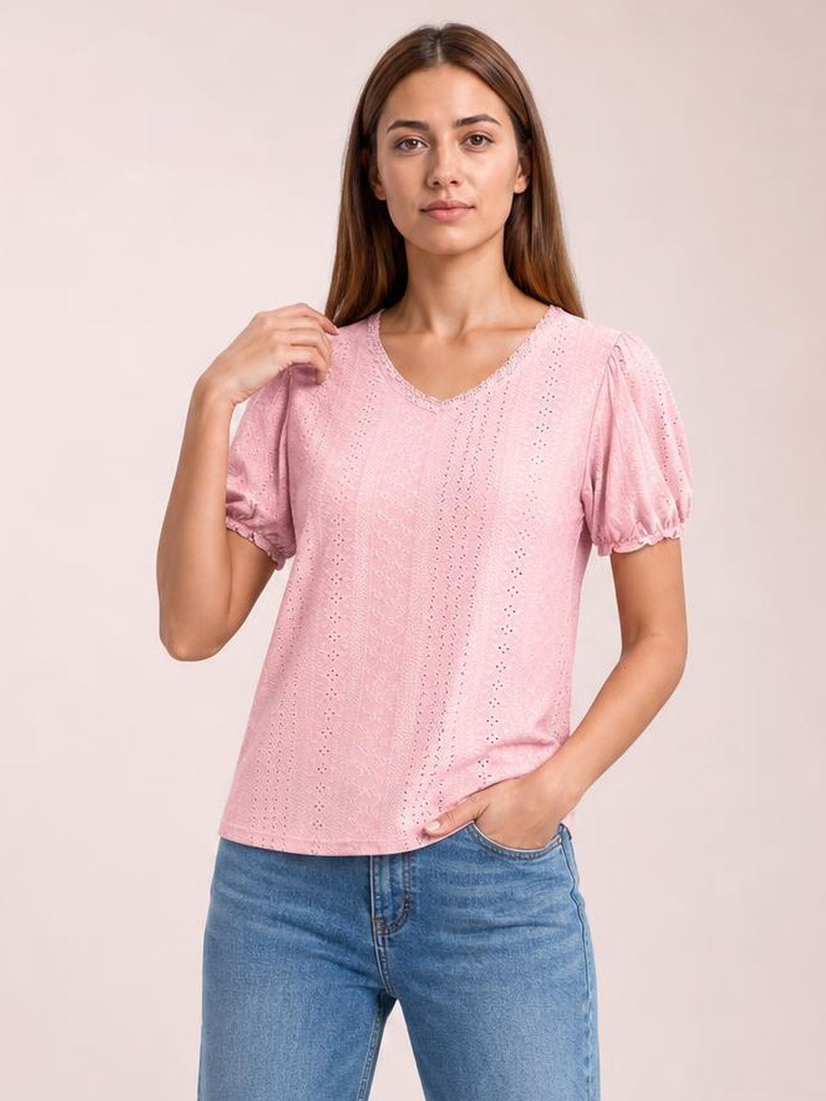 Model poses in a pink eyelet blouse with a round neckline, short puff sleeves, delicate frill trim, and a relaxed straight silhouette.