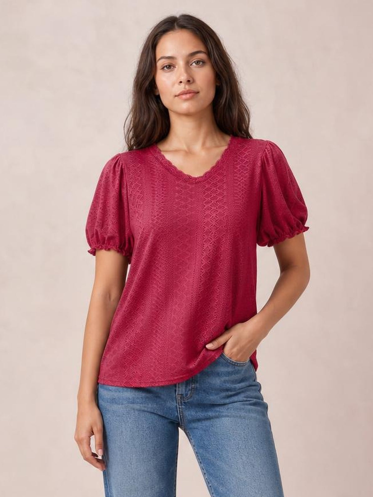 Model poses in a raspberry eyelet blouse with a round neckline, delicate frill trim, short puff sleeves, and a relaxed straight silhouette.