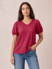Model poses in a raspberry eyelet blouse with a round neckline, delicate frill trim, short puff sleeves, and a relaxed straight silhouette.