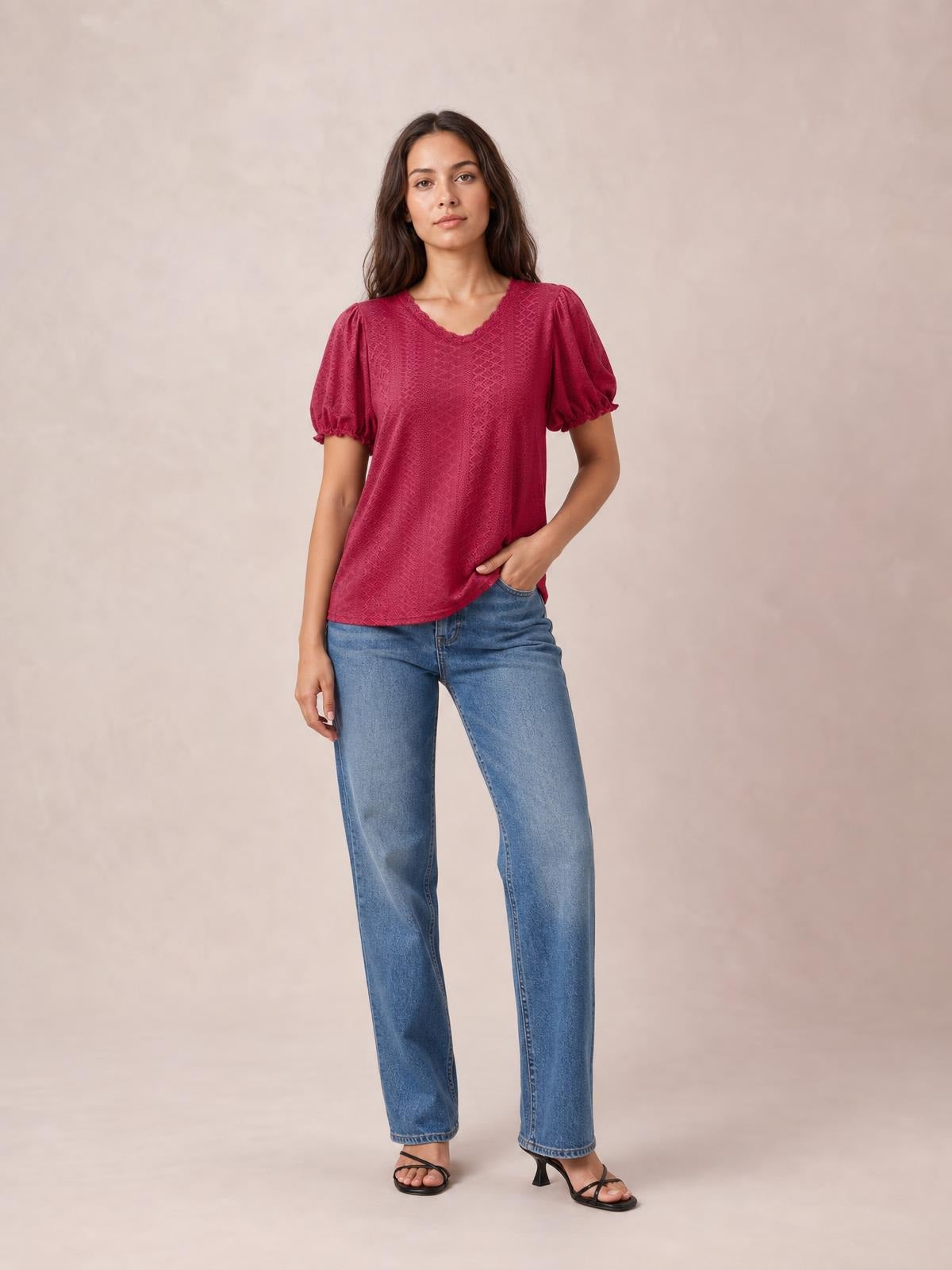 A model stands in a magenta eyelet blouse with a round neckline, short puff sleeves, delicate frill cuffs, and a relaxed straight silhouette.