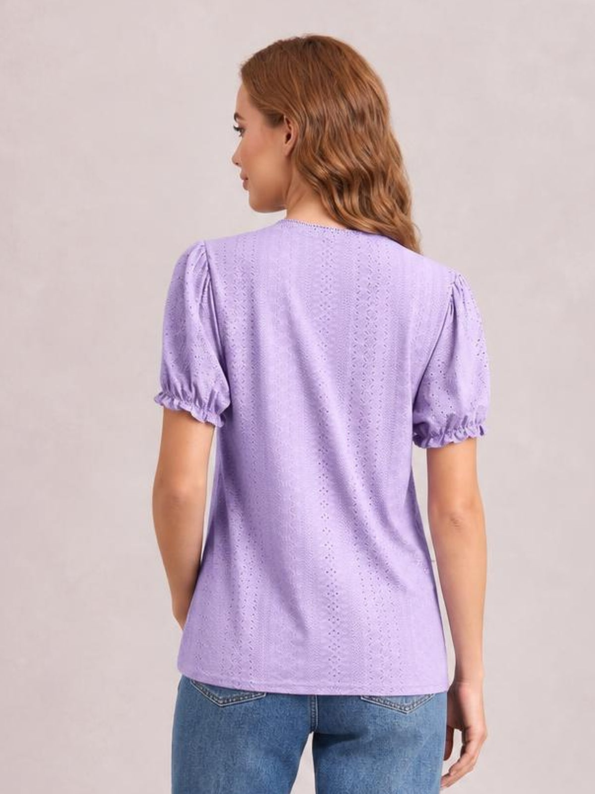 A model wears a lavender eyelet blouse with a round neck, short puff sleeves with frilled elastic cuffs, and a relaxed straight silhouette, shown from behind.
