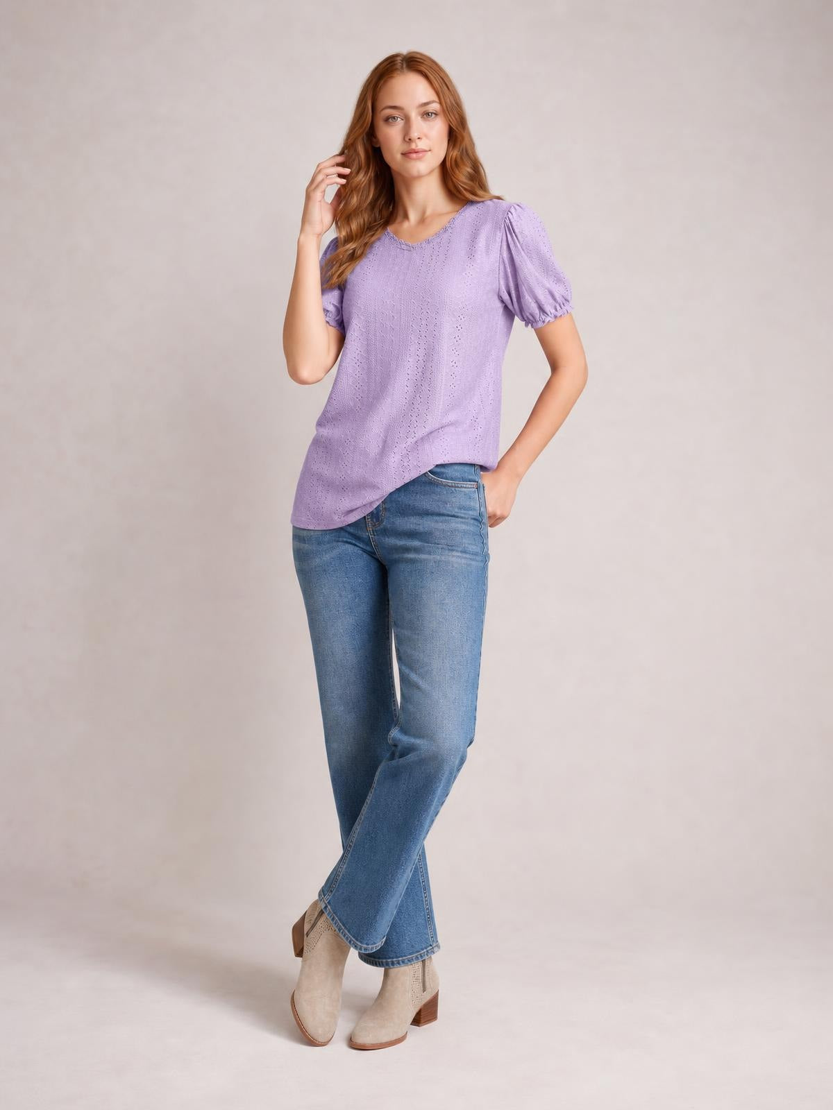 A model poses in a lavender eyelet blouse with a round neck, delicate frill, short puff sleeves, and a relaxed silhouette styled with jeans.