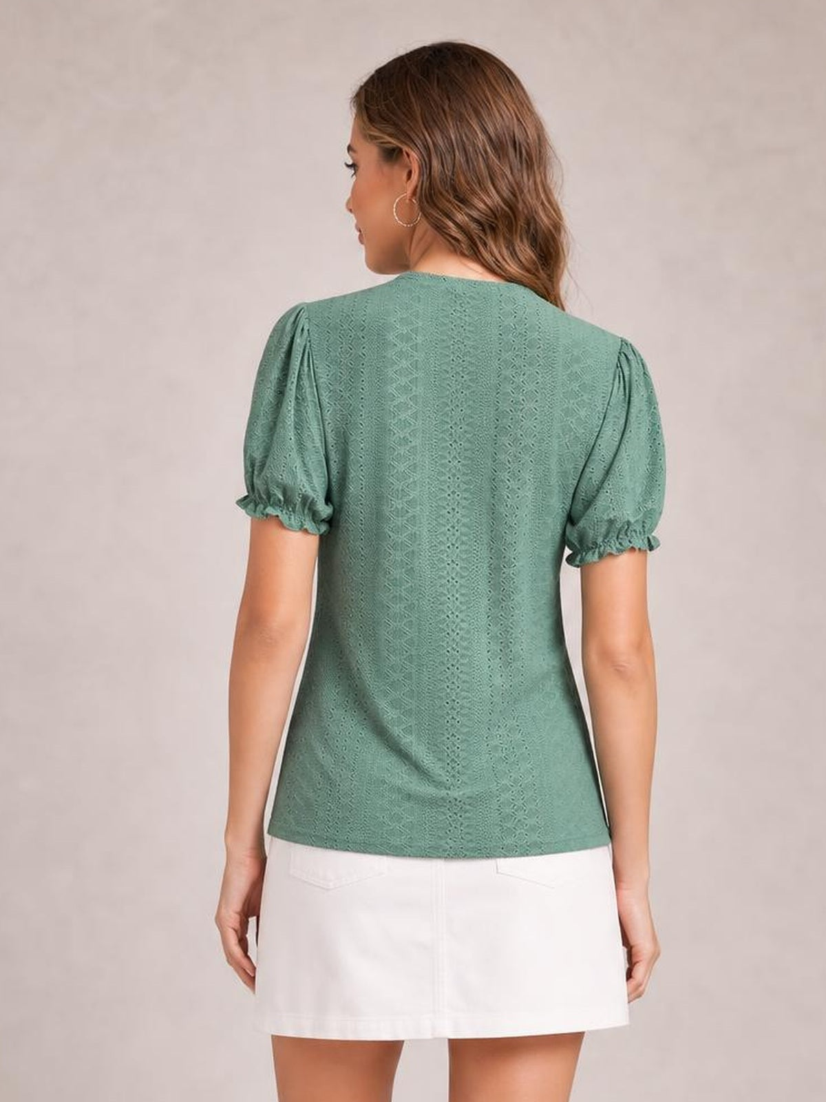 Model shown from behind wearing a mint green eyelet blouse with a straight silhouette, round neck, short puff sleeves, and delicate frill cuffs.