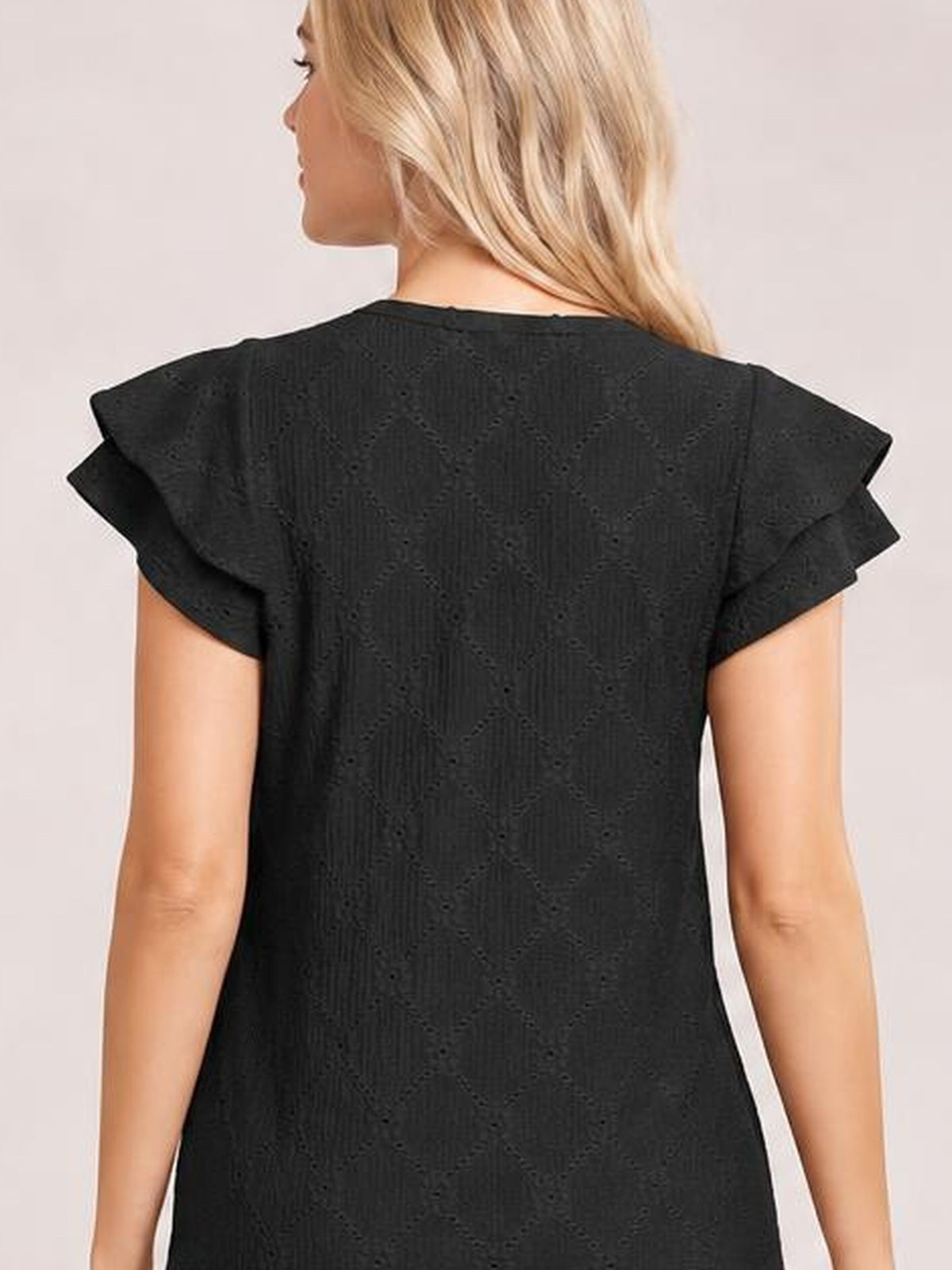Model shown from behind wearing a black eyelet top with layered ruffled cap sleeves and a relaxed, straight silhouette.