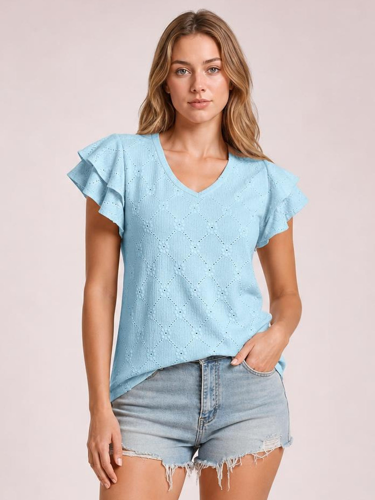 Model wearing a light blue eyelet top with a V-neck, layered ruffled cap sleeves, lace detailing, and a relaxed straight silhouette.