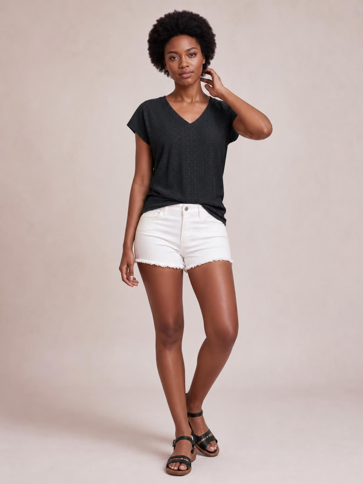 Model poses in a black eyelet V-neck short sleeve top with a relaxed silhouette, subtle stretch, and vertical textured construction.
