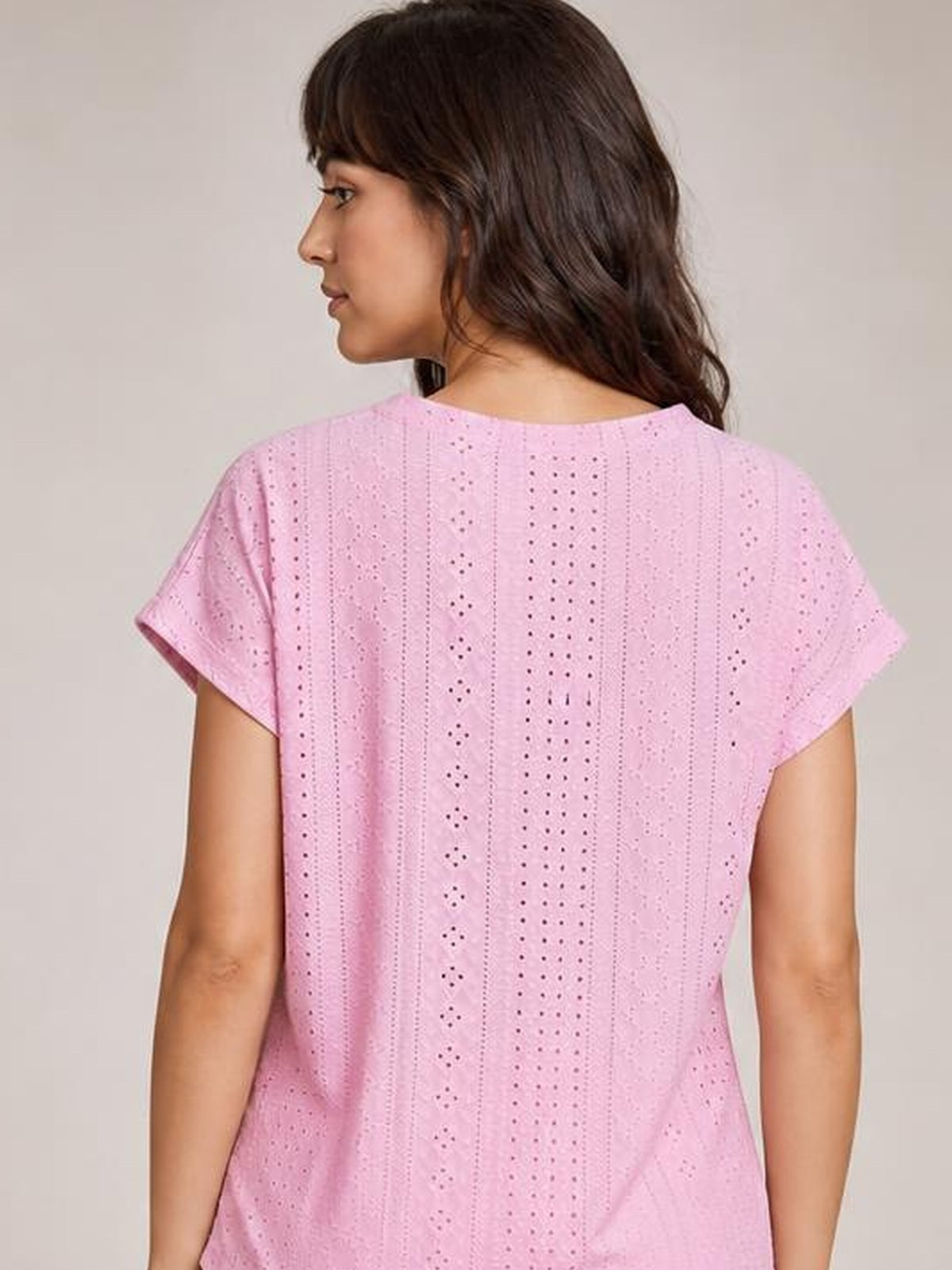 Model shown from the back in a pink eyelet short-sleeve top with a relaxed, straight silhouette and vertically patterned cutout construction.