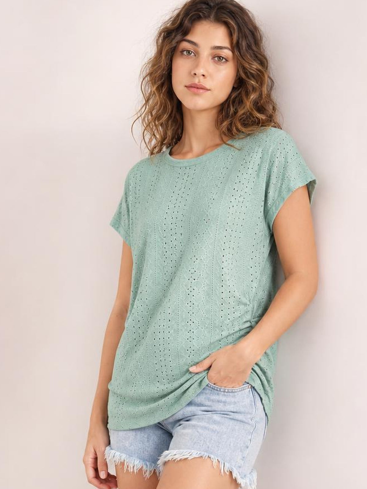 Model wears a mint green eyelet short sleeve top with a relaxed silhouette, rounded neckline, and lightweight perforated construction.