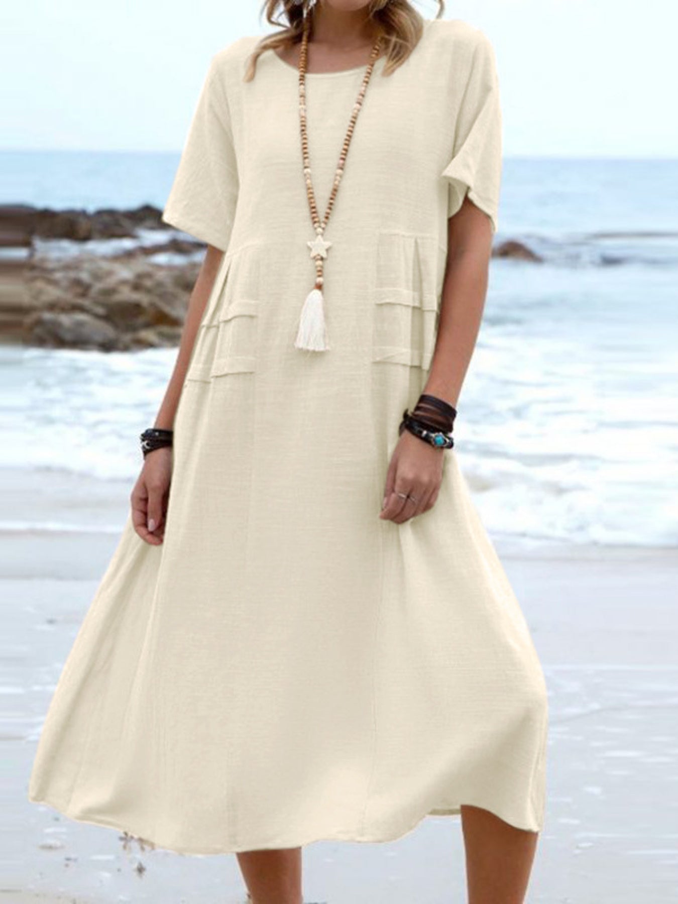 Plus size loose midi dress with short sleeves and pockets shown in cream and black by the beach