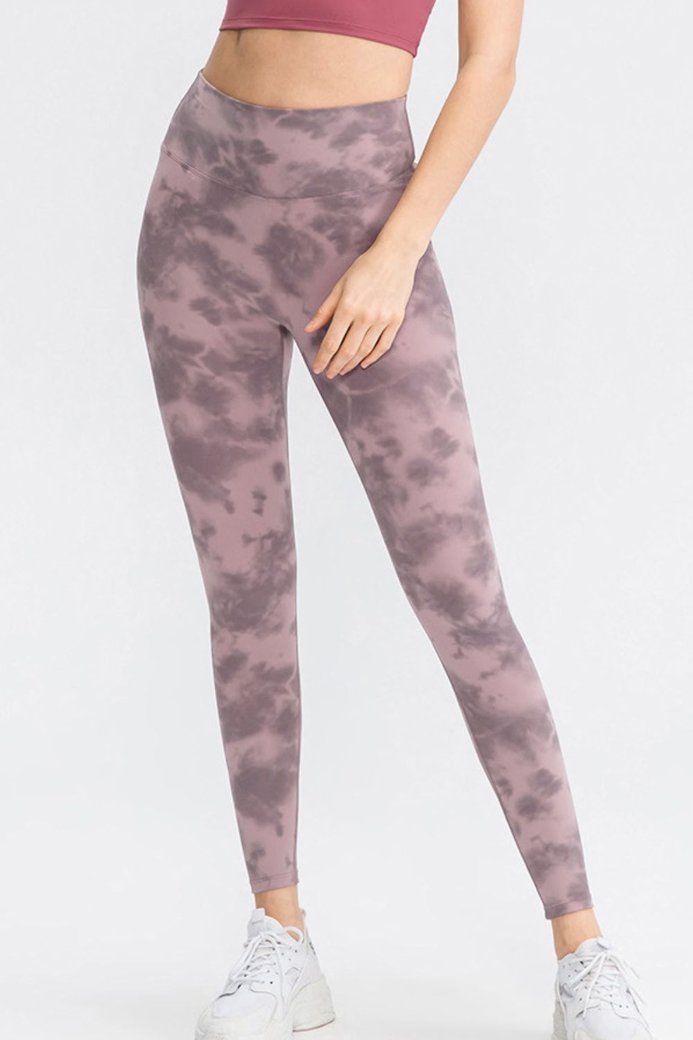 Model stands with one hand on her thigh wearing mauve and gray tie-dye slim-fit long sports pants with a wide waistband and ankle-length silhouette.