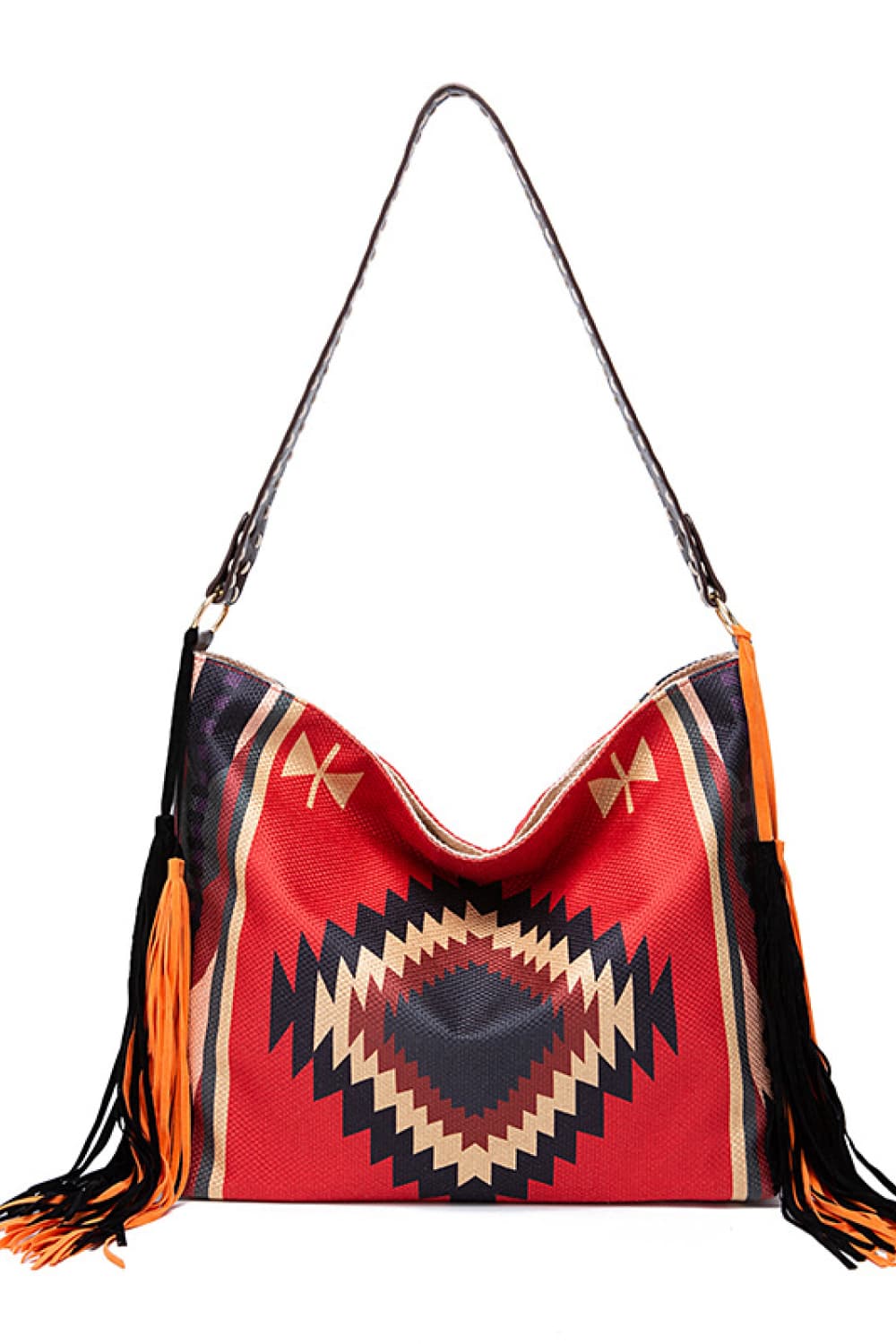 Oversize geometric canvas tote bag in red with a bold zigzag pattern, slouchy silhouette, long shoulder strap, and black-and-orange fringe detailing.