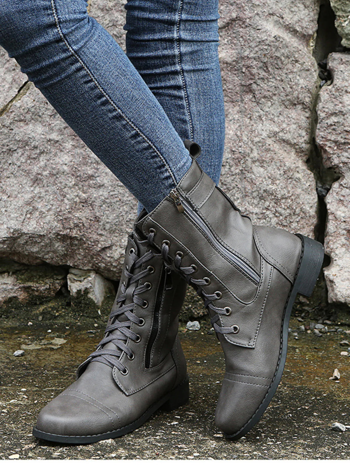 A model poses in gray PU leather lace-up boots with side zippers, stitched panels, low heels, and sturdy rubber soles.
